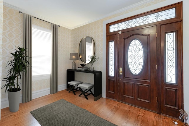 foyer entrance featuring light hardwood / wood-style flooring, ornamental molding, and a healthy amount of sunlight