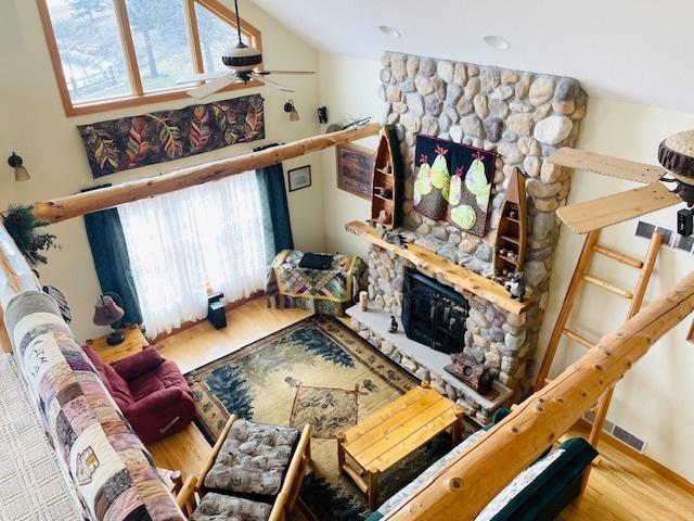 living room featuring hardwood / wood-style floors, ceiling fan, a fireplace, and vaulted ceiling