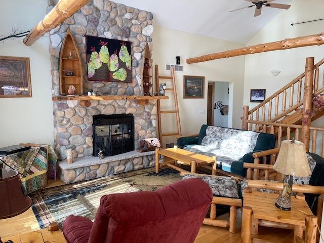 living room with ceiling fan, a fireplace, wood-type flooring, and lofted ceiling