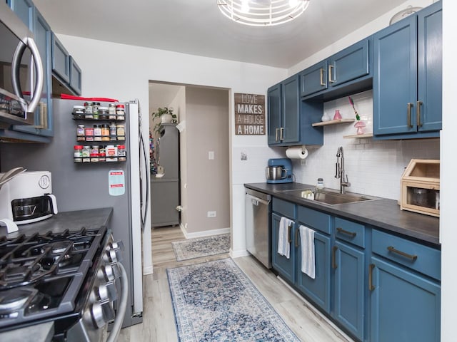 kitchen with sink, tasteful backsplash, blue cabinets, appliances with stainless steel finishes, and light wood-type flooring