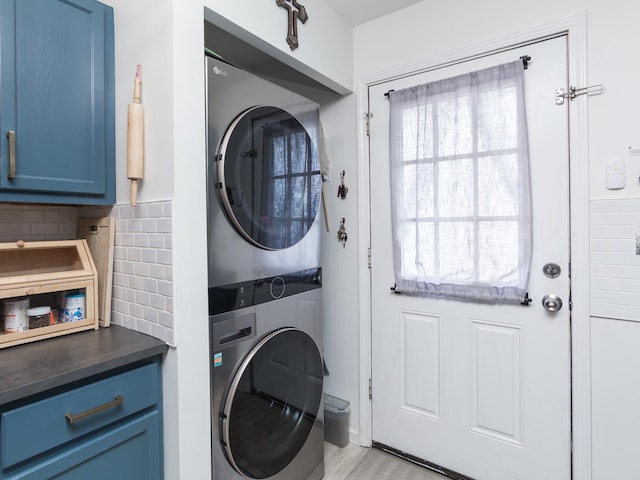 laundry room with cabinets, stacked washing maching and dryer, and light hardwood / wood-style floors