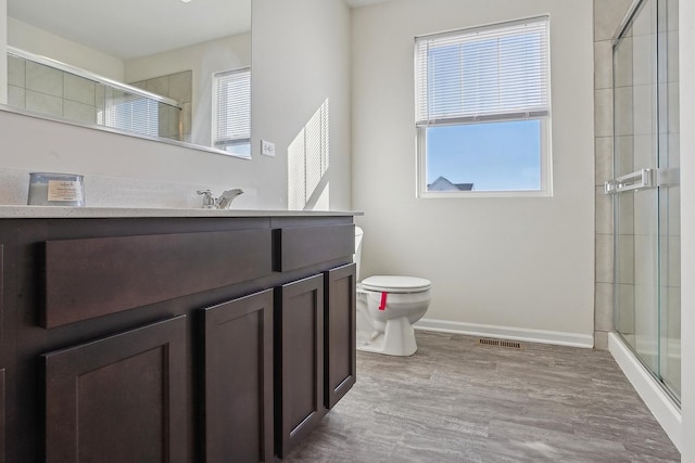 bathroom featuring vanity, a shower with door, and toilet