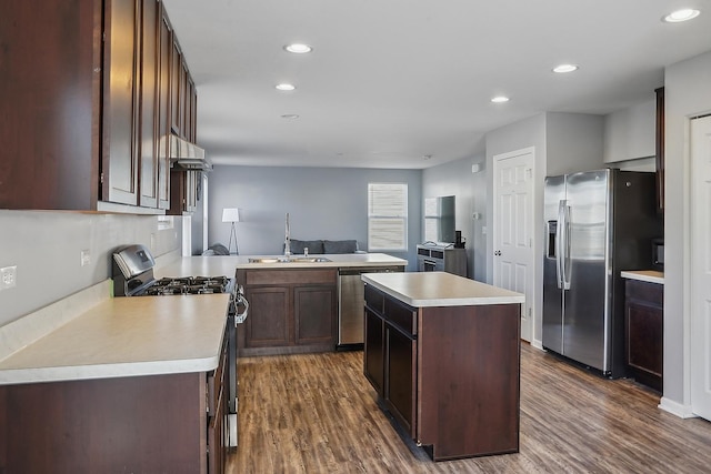 kitchen with sink, a center island, dark hardwood / wood-style floors, kitchen peninsula, and stainless steel appliances