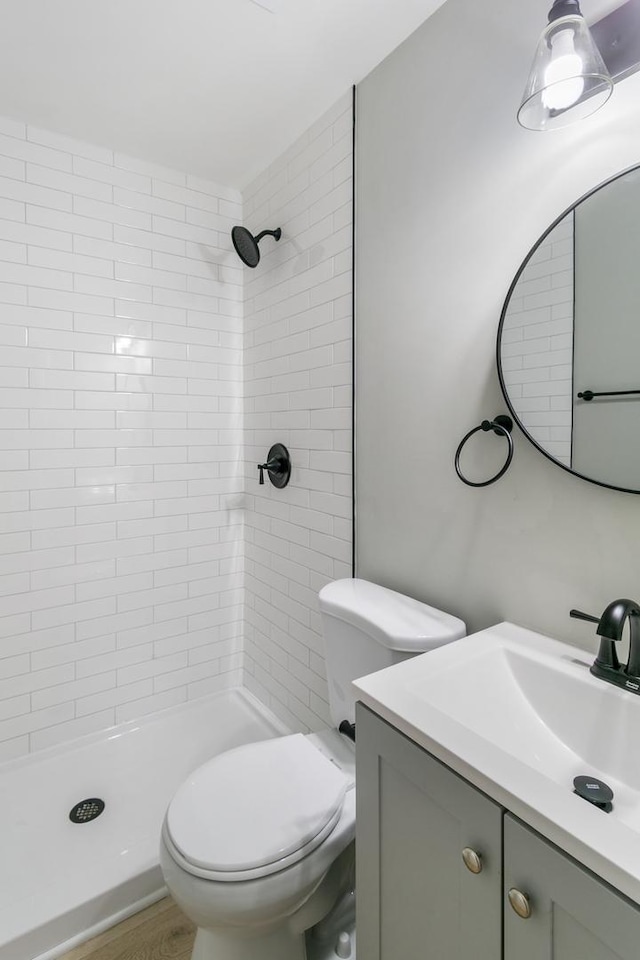 bathroom featuring tiled shower, hardwood / wood-style floors, vanity, and toilet