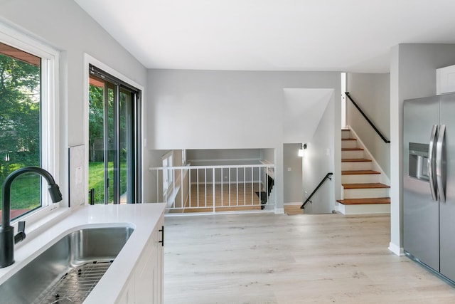 kitchen featuring sink, white cabinets, light hardwood / wood-style floors, and stainless steel refrigerator with ice dispenser