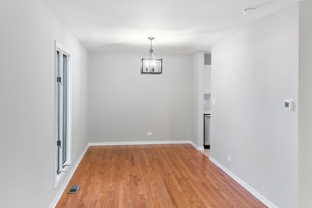 unfurnished room with light hardwood / wood-style flooring and a notable chandelier