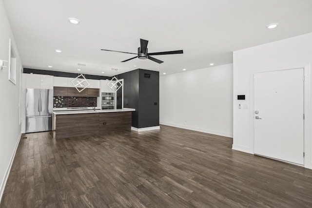 unfurnished living room featuring ceiling fan and dark hardwood / wood-style flooring