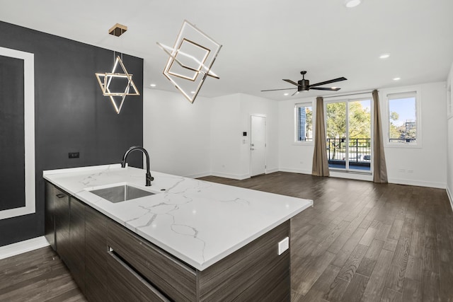 kitchen featuring ceiling fan, sink, light stone counters, dark hardwood / wood-style flooring, and pendant lighting