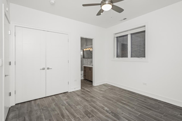 unfurnished bedroom with connected bathroom, a closet, ceiling fan, and dark wood-type flooring