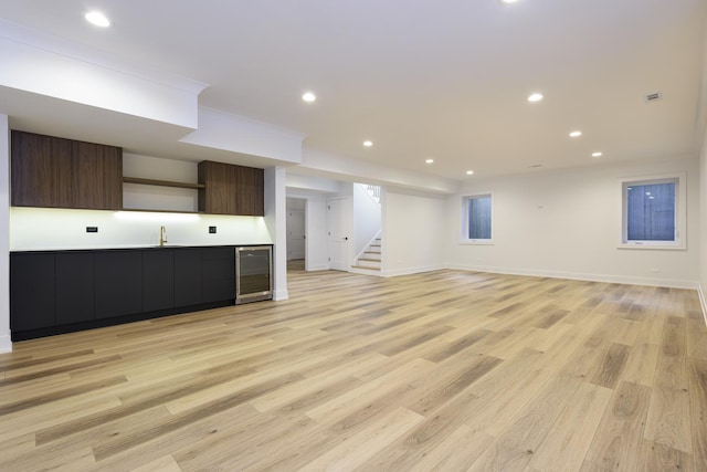 unfurnished living room with wine cooler, sink, and light wood-type flooring