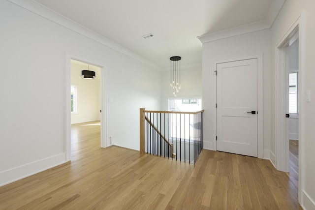 hallway featuring crown molding, a chandelier, and light wood-type flooring