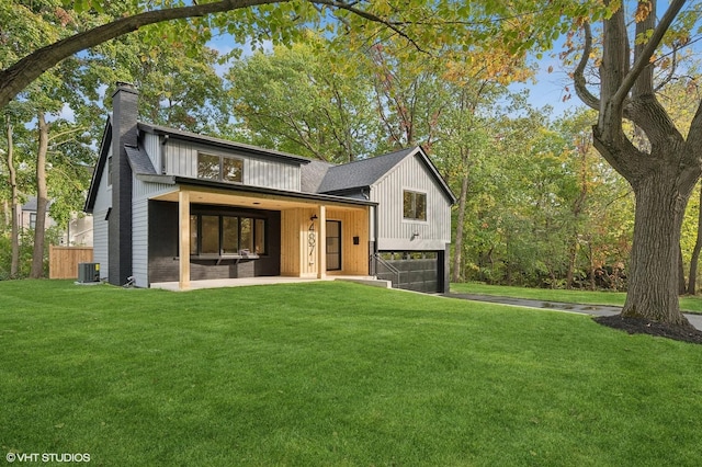 view of front of house featuring cooling unit, a front lawn, covered porch, and a garage