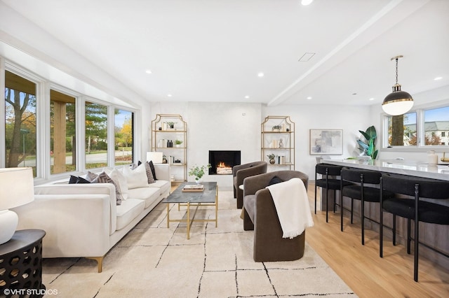 living room featuring beamed ceiling, light hardwood / wood-style floors, and a wealth of natural light