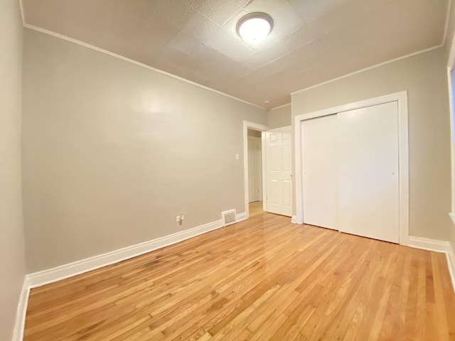 unfurnished bedroom featuring ornamental molding, a closet, and light hardwood / wood-style flooring