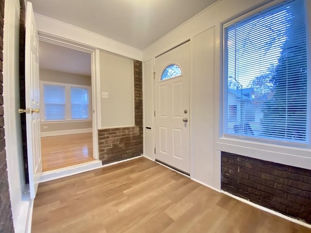 entryway with brick wall and wood-type flooring