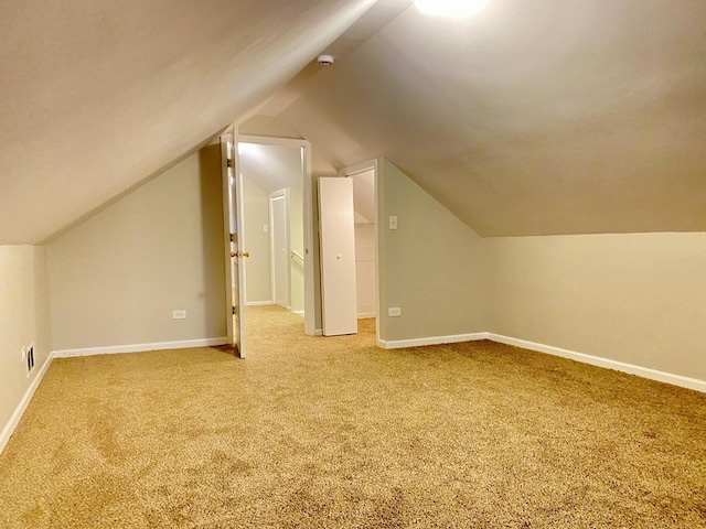 additional living space featuring vaulted ceiling and carpet flooring