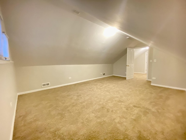 additional living space with light colored carpet and lofted ceiling