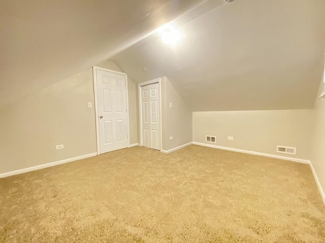 additional living space with light colored carpet and vaulted ceiling