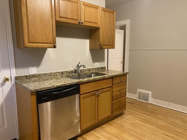 kitchen with light wood-type flooring, dishwasher, dark stone countertops, and sink