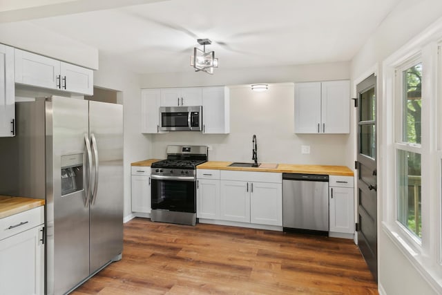 kitchen featuring butcher block countertops, sink, white cabinets, and appliances with stainless steel finishes