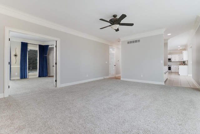 spare room with ceiling fan, crown molding, and light carpet