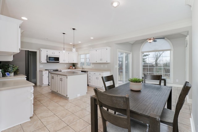 tiled dining room with crown molding and ceiling fan