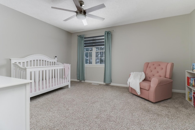 bedroom with a crib, carpet, and ceiling fan