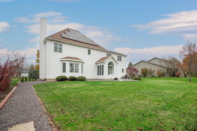 rear view of house featuring a lawn and solar panels