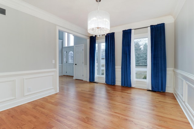 unfurnished room with light hardwood / wood-style floors, crown molding, and an inviting chandelier