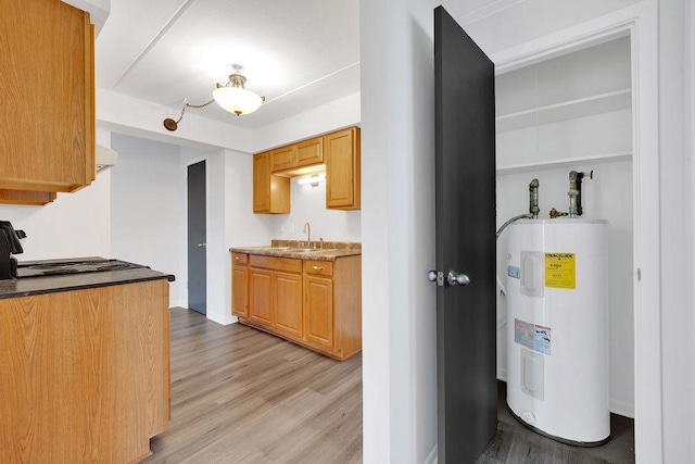 kitchen featuring light wood-type flooring, electric water heater, sink, range, and range hood