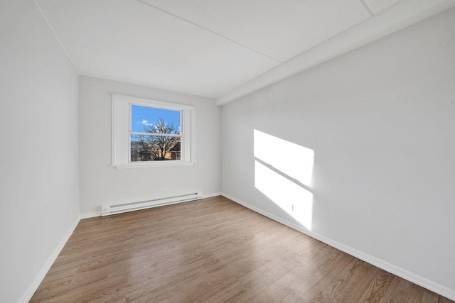 spare room featuring baseboard heating and light hardwood / wood-style flooring