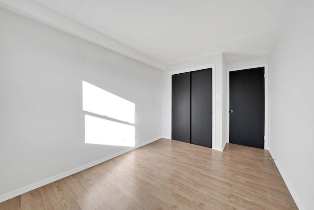 unfurnished bedroom featuring light wood-type flooring and a closet