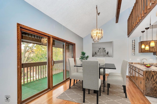 dining space with sink, vaulted ceiling with beams, light wood-type flooring, a textured ceiling, and a chandelier