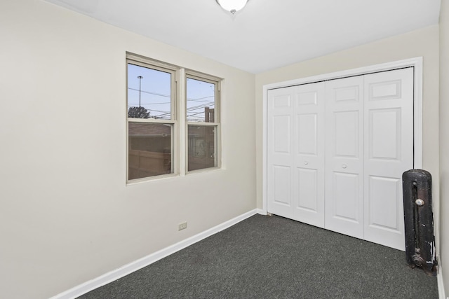 unfurnished bedroom with a closet and dark carpet