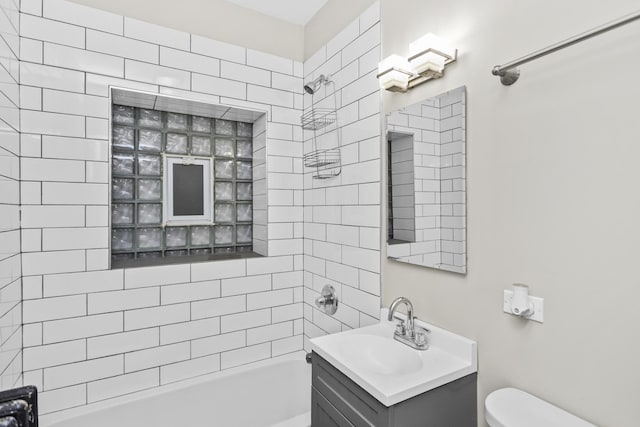 full bathroom featuring vanity, tiled shower / bath combo, and toilet