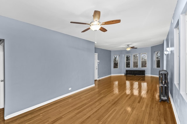 unfurnished living room with ceiling fan, radiator heating unit, and wood-type flooring