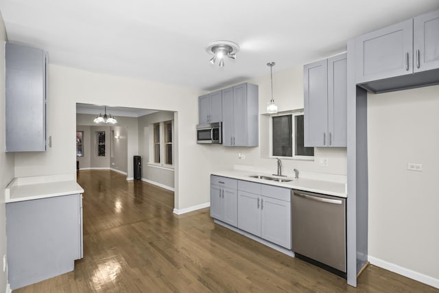 kitchen with a chandelier, appliances with stainless steel finishes, pendant lighting, and sink