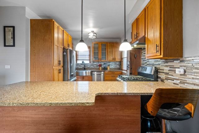 kitchen featuring kitchen peninsula, decorative backsplash, stainless steel appliances, and light stone counters