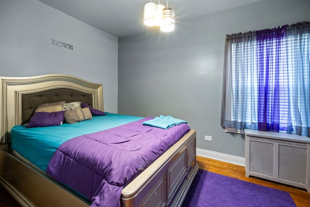 bedroom with dark hardwood / wood-style flooring and radiator