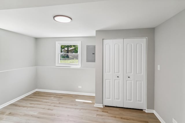 unfurnished bedroom with light wood-type flooring, electric panel, and a closet