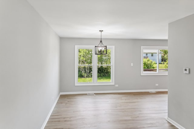 unfurnished dining area featuring a notable chandelier and light hardwood / wood-style floors