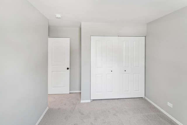 unfurnished bedroom featuring a closet and light colored carpet