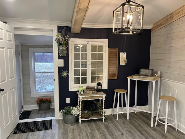 dining space featuring hardwood / wood-style flooring, crown molding, beam ceiling, and a chandelier