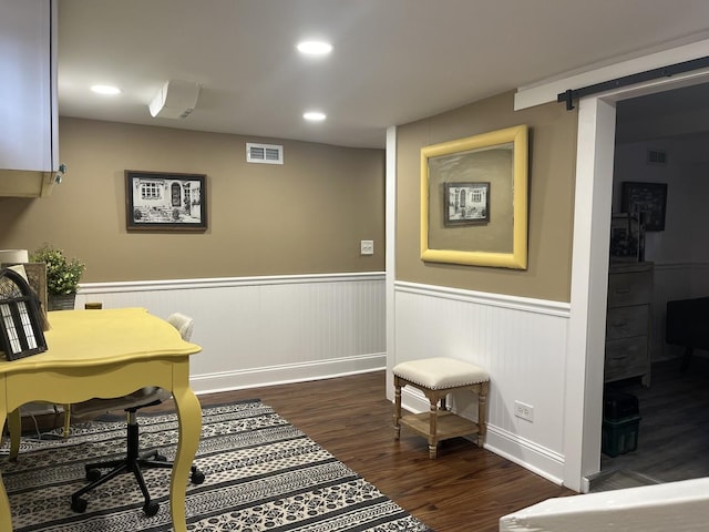 home office with dark wood-type flooring and a barn door