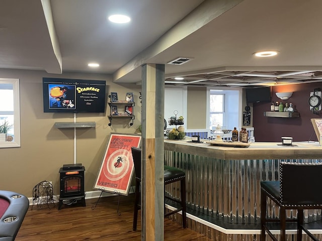 bar with wood-type flooring and a wood stove