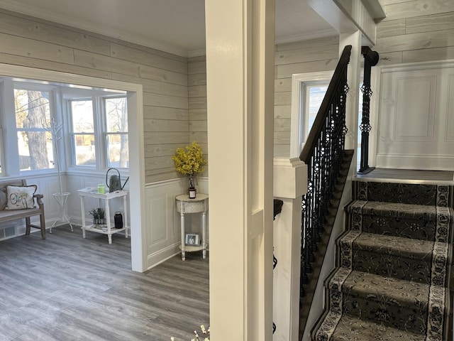 stairway with hardwood / wood-style flooring and ornamental molding