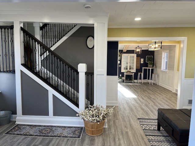 stairs with a chandelier, crown molding, and wood-type flooring