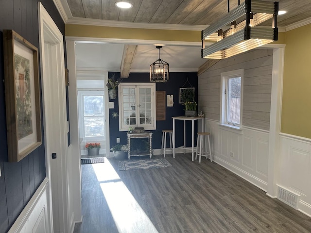 interior space featuring dark hardwood / wood-style flooring, crown molding, beamed ceiling, and an inviting chandelier