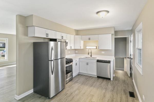 kitchen featuring light hardwood / wood-style floors, white cabinetry, sink, and appliances with stainless steel finishes