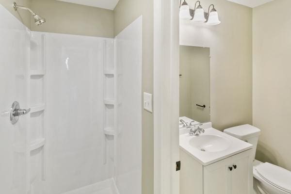 bathroom featuring toilet, a shower, and vanity